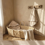 Gepersonaliseerde beige baby badcape met borduring van naam in rieten moosesmandje