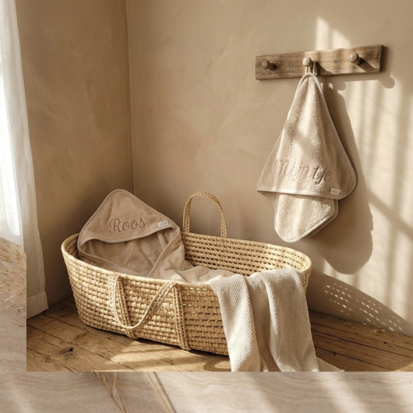 Gepersonaliseerde beige baby badcape met borduring van naam in rieten moosesmandje